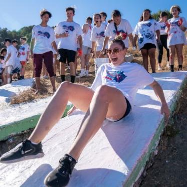 A student yelling and sliding down a letter at paint the SMC